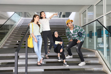 Young asian malay chinese man woman indoor stair corridor campus book file folder laptop computer phone sit stand mingle talk study