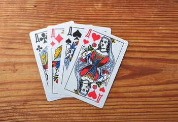 four playing cards of queens lying face up isolated on wooden background