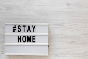 'Stay home' words on a lightbox on a white wooden background, top view. Overhead, from above, flat lay. Copy space.