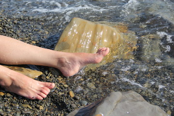 Two women's feet on a shingle beach by the sea