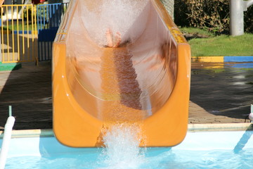 A girl in a water Park has rolled down a slide and the spray is flying