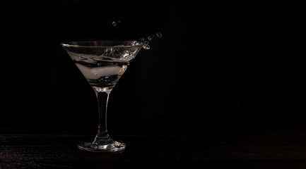 alcohol coctail glass on a black background. Splash of cocktail. horizontal banner for designers