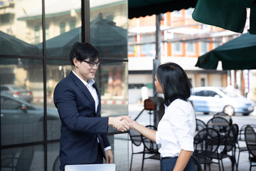 Asian and Caucasian business man shaking hands after concluding the agreement at a co-working space, Coffee shop. business success concept