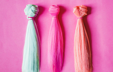 Colorful dolls hair on pink background