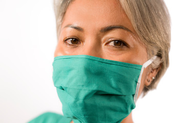 isolated white background portrait of mature attractive and confident medicine doctor woman or hospital nurse in medical gown and face mask looking at the camera