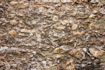 old brown stone wall of dilapidated historic building, background with architectural elements