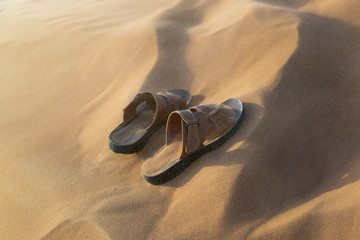 Men's sandals in a sandstorm. Men's summer shoes brought in sand in the desert.