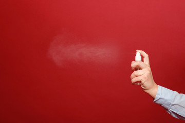 coronavirus pandemic, close-up spray antiseptic on red background in hand of woman