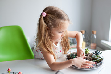 Beautiful girl plants succulents in a glass florarium at a lesson in a creativity studio