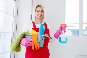 A young woman in a mask and gloves holds a spray bottle in her hands. Concept art for cleaning rooms and the prevention of viral diseases.