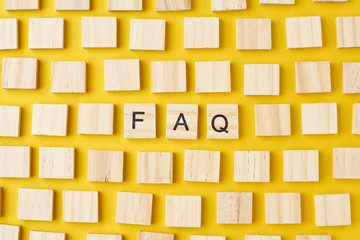 Wooden blocks with abbreviation FAQ on the yellow background, top view. Frequently asked questions...