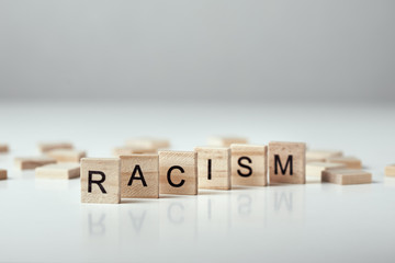 Concept of racism and misunderstanding between people, prejudice and discrimination. Wooden block with word racism on the white backround