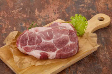 Raw pork steak over wooden board