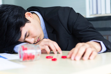 A young Asian businessman begins to have symptoms similar to Covid-19. He is a sleep at working room after taking antipyretics select focus as people