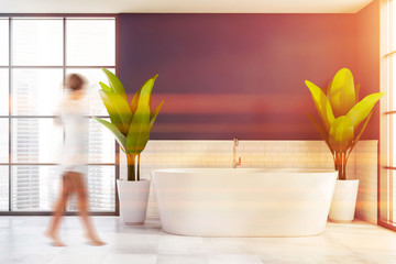 Woman walking in white and blue bathroom with tub