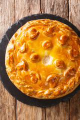 layered pie Kurnik stuffed with chicken potatoes and onions close-up on a slate board. Vertical top view © FomaA