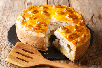 Festive Russian Kurnik sliced pie stuffed with chicken, potatoes and onions close up on a slate board. horizontal © FomaA