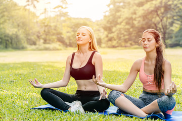 Beautiful girls teen friend do yoga for healthy in green park holiday sitting relax hand lotus eyes closed concentration posture.