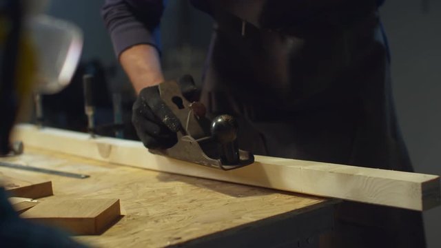 A carpenter uses a planer. Close-up