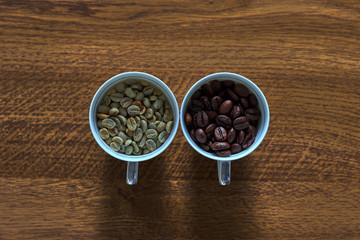 Cup with unroasted coffee beans, and mug with roasted beans