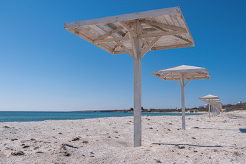 Parasol. A canopy from the sun. Beach. Sand. Blue sky.