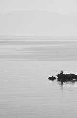 Silhouette of fisherman with fishing rods and lighthouse on the pier. Minimalism.