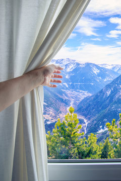 Girl's Hand Pulling Back The Curtain To See The Mountains In The Window.