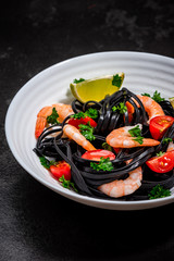 Squid Ink Pasta with Prawns , Tomatoes, Lemon and Herbs. Black Spaghetti, Black Organic Noodles . Mediterranean Gourmet Food