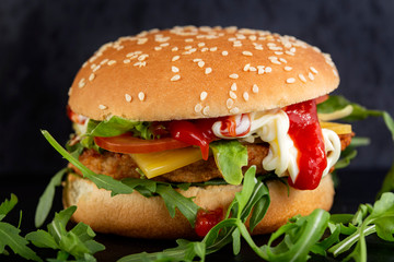 Cheeseburger with a lot of arugula and sauces
