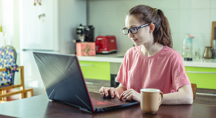Woman remotely works on a laptop at home. Distance work and online education. Useful pastime when have to stay at home
