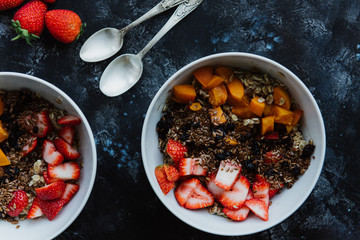 Two plates of oatmeal with strawberries, apricots and flax seeds. Two oatmeal porridge with fruit.