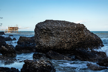 Fototapeta na wymiar the Trabocco, trabucco (fish-trap) with a huge rock in the foreground on the beach of Vasto on Adriatic sea. Vasto, Abruzzo, Italy
