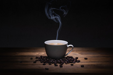a cup of coffee and beans on wooden table, hot drink with steam