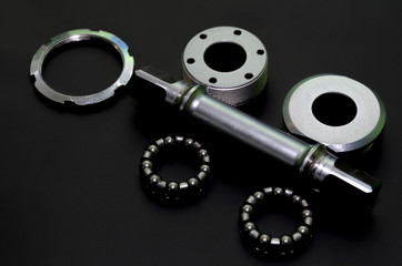 Bicycle repair. Old vintage bike parts on a black background in the studio. Bearing and cup close-up. Instructions or service manual bicycle parts. Replacing and installing the bottom bracket.