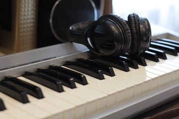 Black headphones on the keyboard, red headphones on the laptop, electronic piano keys