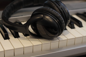 Obraz na płótnie Canvas Black headphones on the keyboard, red headphones on the laptop, electronic piano keys