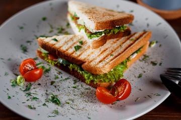 Toasted shredded chicken breast and salad sandwich served on a rustic wooden table wrapped in a brown paper wrapper tied with string with vignetting and copyspace.