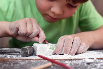 Children having fun with archaeology excavation kit. Boy plays an archaeologist excavated, training...