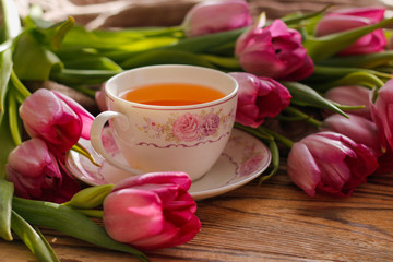 Fototapeta na wymiar tulips and a cup of tea on wooden background