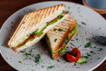Toasted shredded chicken breast and salad sandwich served on a rustic wooden table wrapped in a brown paper wrapper tied with string with vignetting and copyspace.