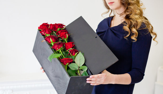 man gives red roses in an original box to his beloved woman
