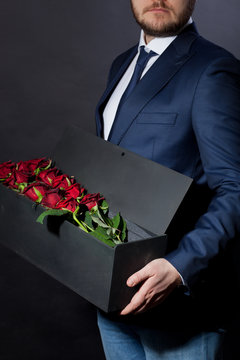 man gives red roses in an original box to his beloved woman