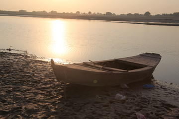 Fototapeta na wymiar Old wooden boat at river shore with sunset. Old boat vintage look with sunset horizon in evening