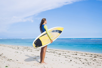 Adult woman with surf board preparing for swimming while standing on sea shore