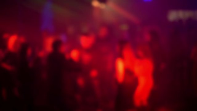 blurred silhouettes of a crowd of people dancing on the dance floor in a nightclub