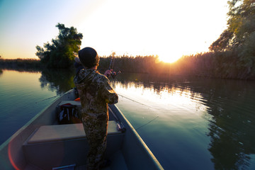 Anglers fishing from the boat on the calm river in Astrakhan Region in Russia. Astrakhan is a...