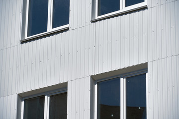 facade of a new multistory building with white and green metal siding, many Windows