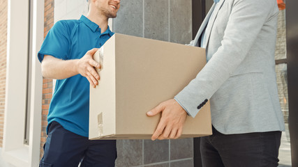 Delivery Man Gives Postal Package to a Business Customer, Who Signs Electronic Signature POD Device. In Stylish Modern Urban Office Area Courier Delivers Cardboard Box Parcel to a Man.