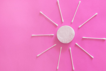 cotton buds and makeup cleaning discs on a pink background with copy space
