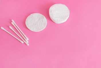 cotton buds and makeup cleaning discs on a pink background with copy space